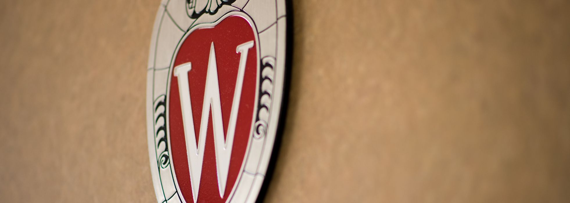 A shield Wisconsin logo on a tan wall