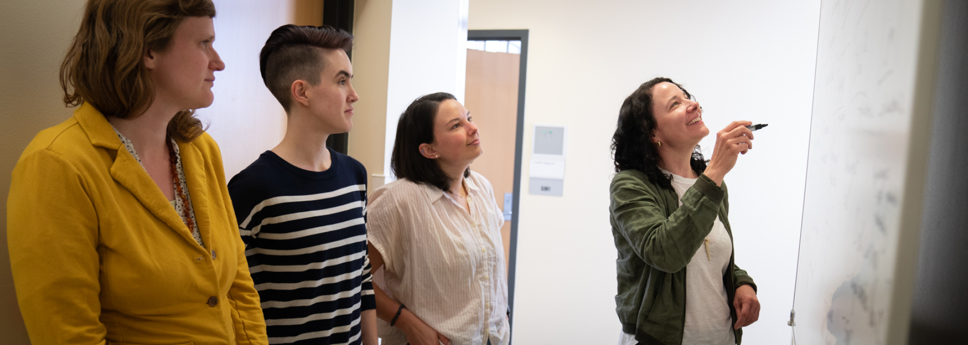 Photo of Dr. Caitlin Pepperell teaching 3 learners in her lab