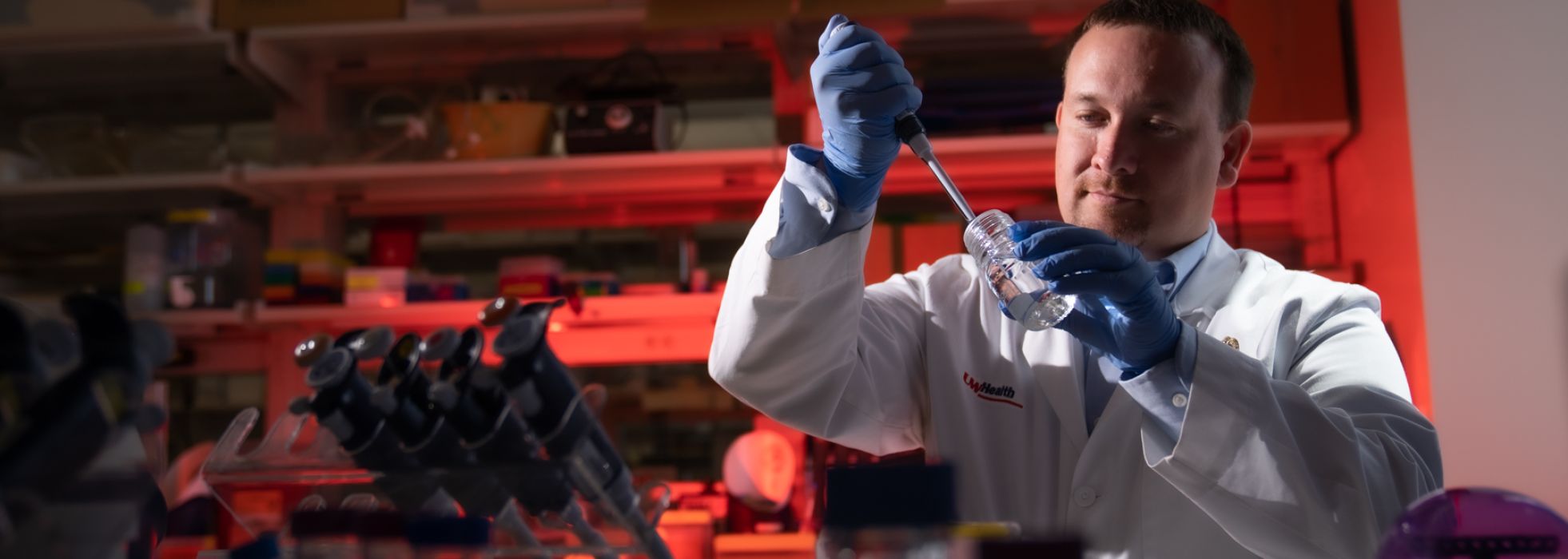 Dr. Dustin Deming in a lab using a pipette