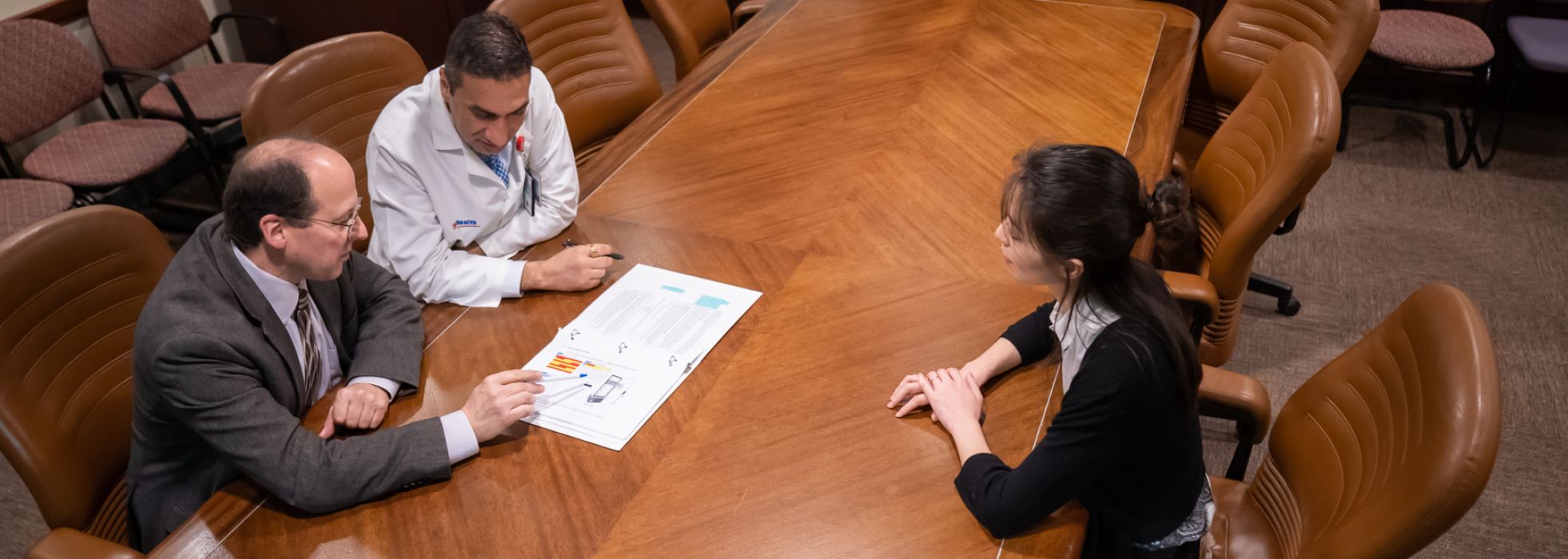 Overhead photo of Dr. Brad Astor talking with learners at a conference room table
