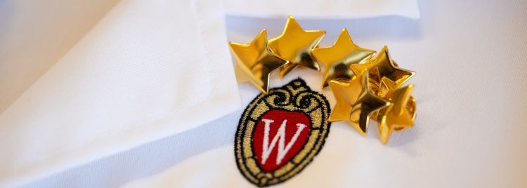 Star pins on a white doctor's coat with the UW crest