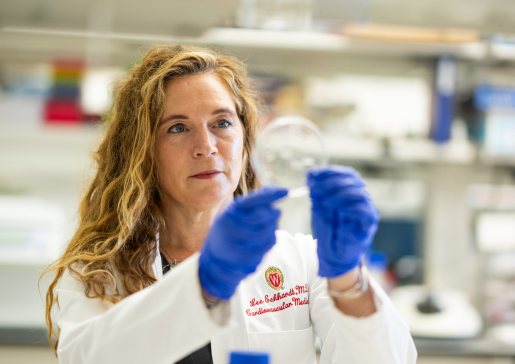 Closeup of Dr. Lee Eckhardt wearing white coat holding petri dish in the lab