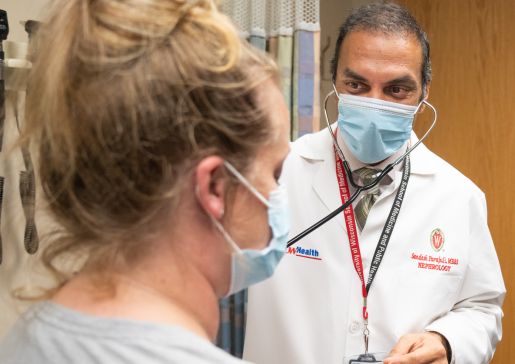 Dr. Sandesh Parajuli wearing a surgical mask examining a patient in the clinic